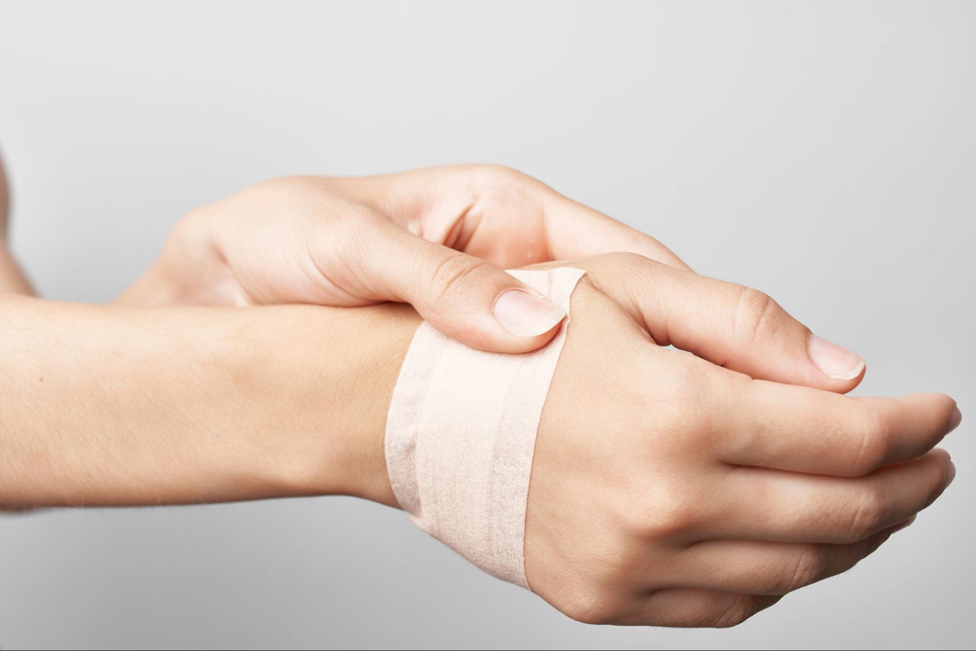 A woman holding her hand with a bandage on it.