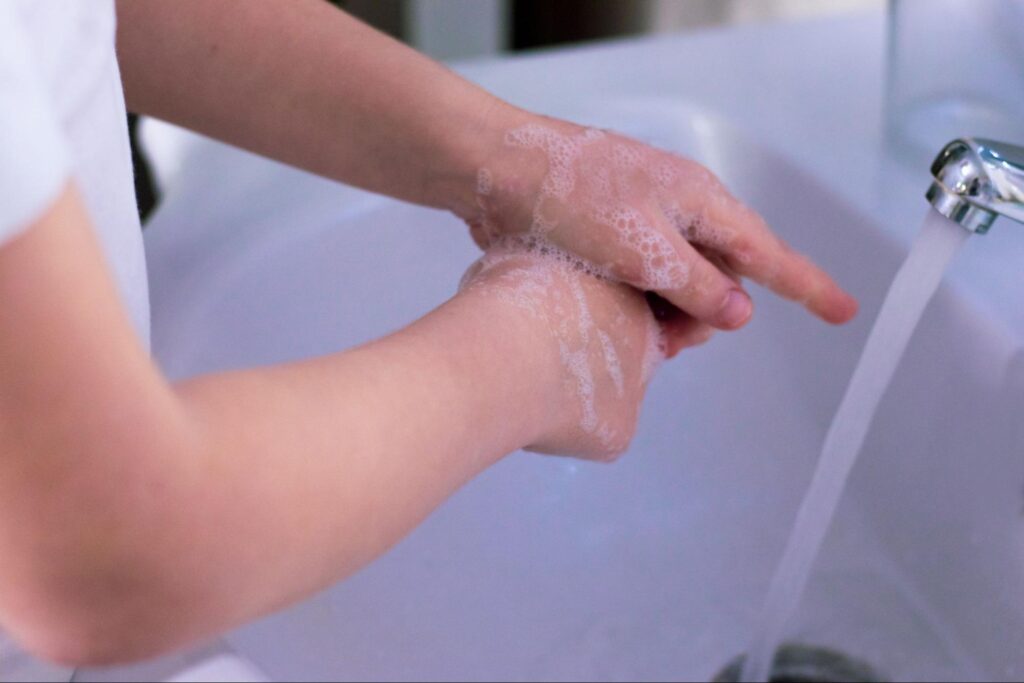 A doctor washing his hands thoroughly with soap and water in a sink.