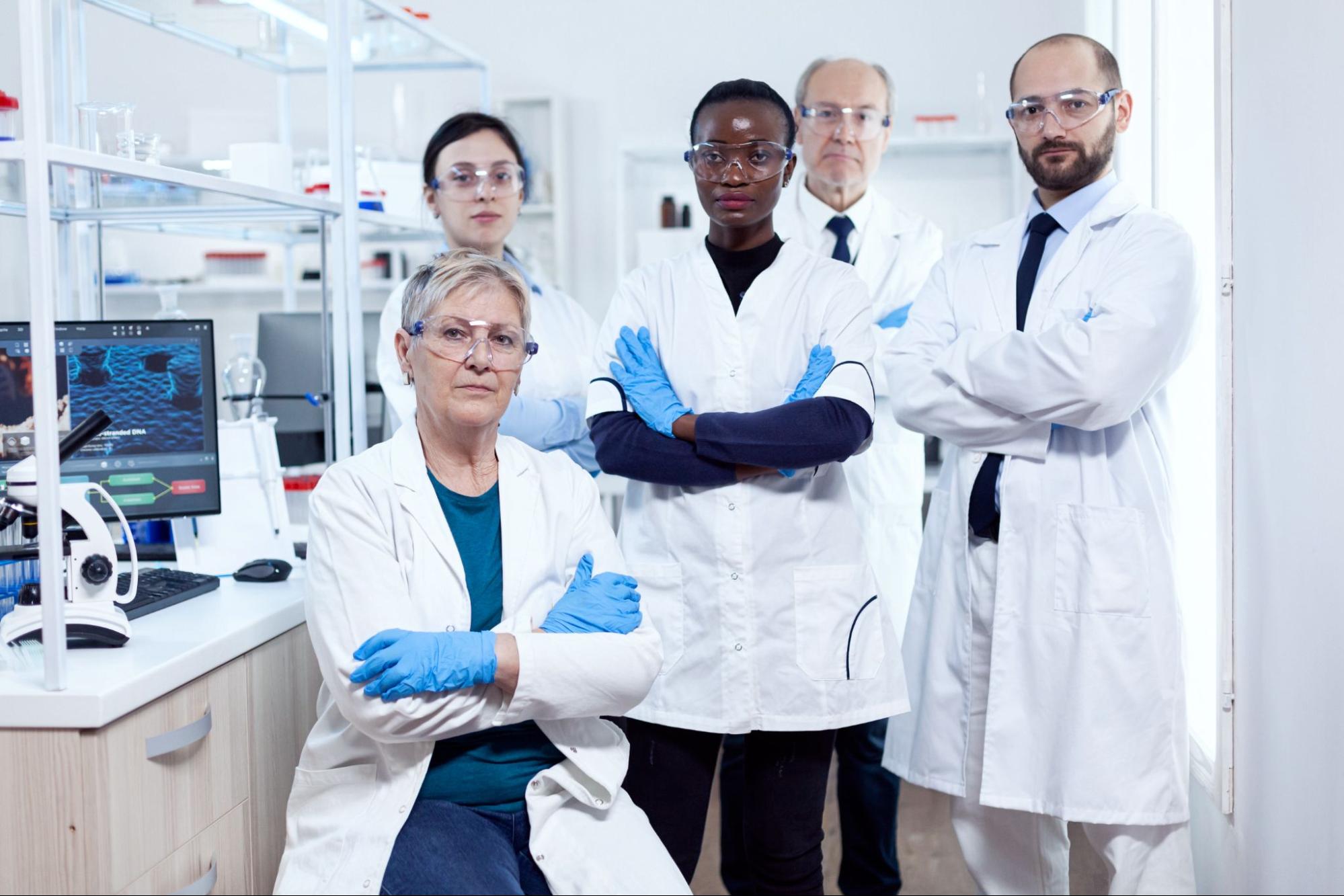 Five professional scientists who study regenerative medicine standing and sitting together in a laboratory.