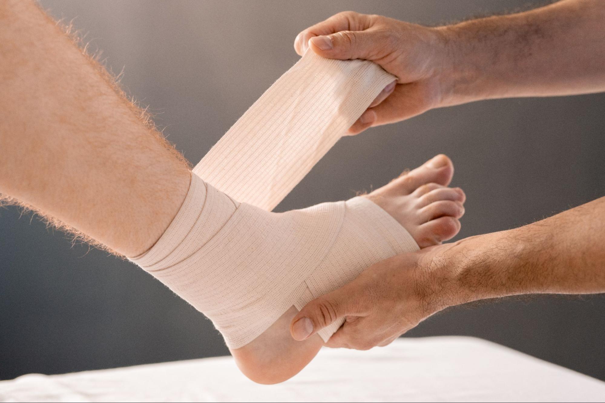 Person applying a bandage to a man’s foot.