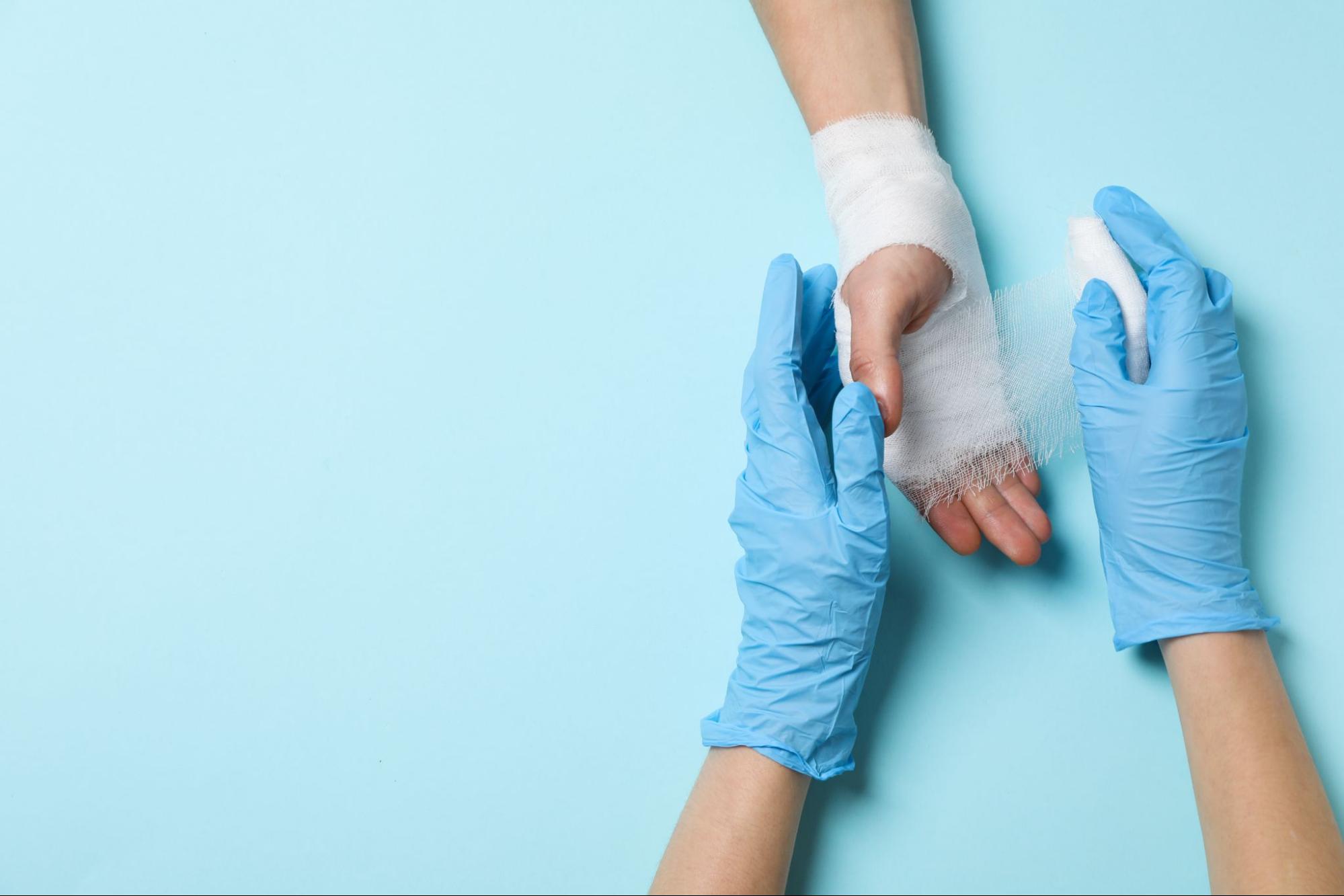 A wound expert wrapping a bandage on a wound on a person’s hand.