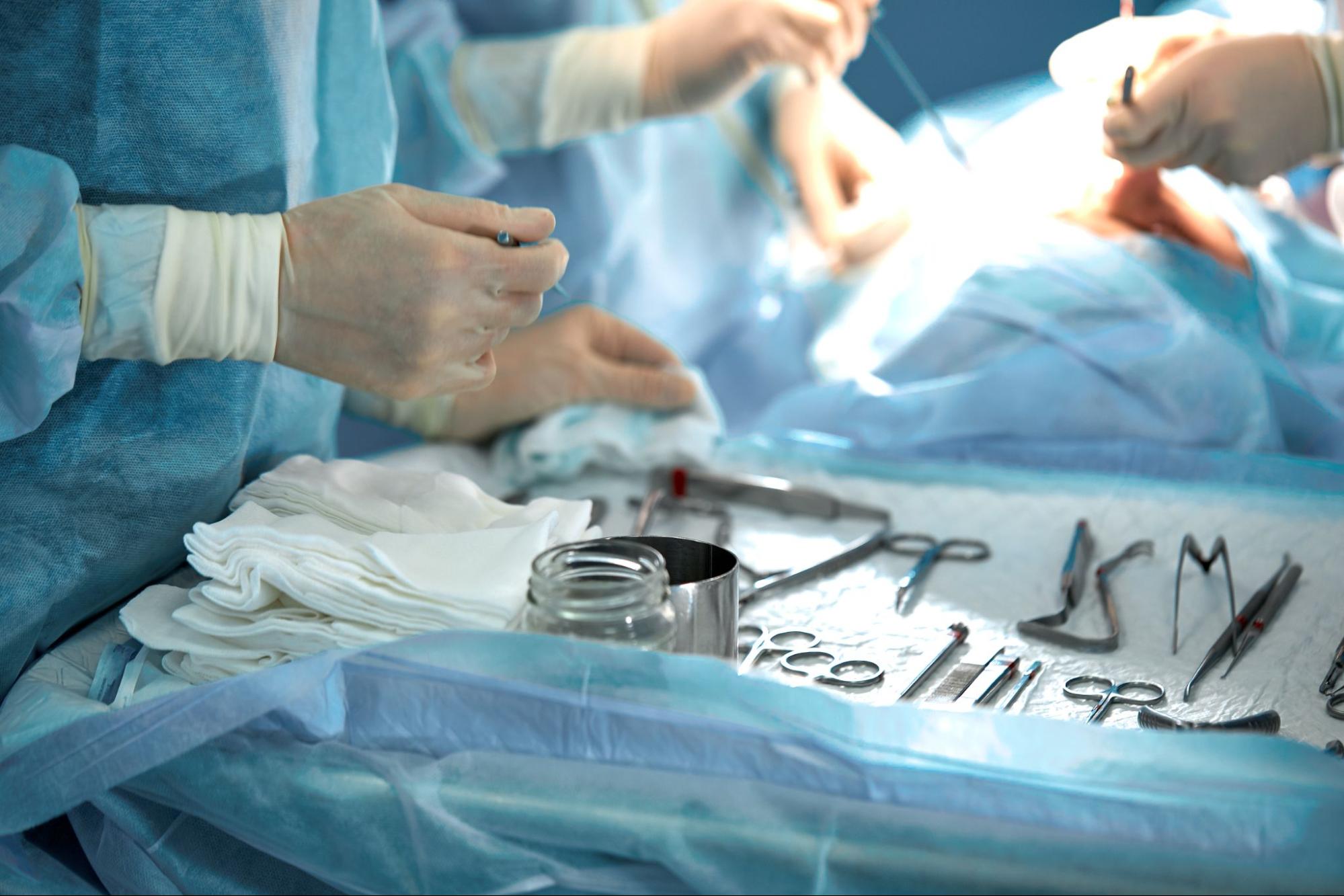 Tools on a tray in an operating room where doctors are performing a surgery on a patient.