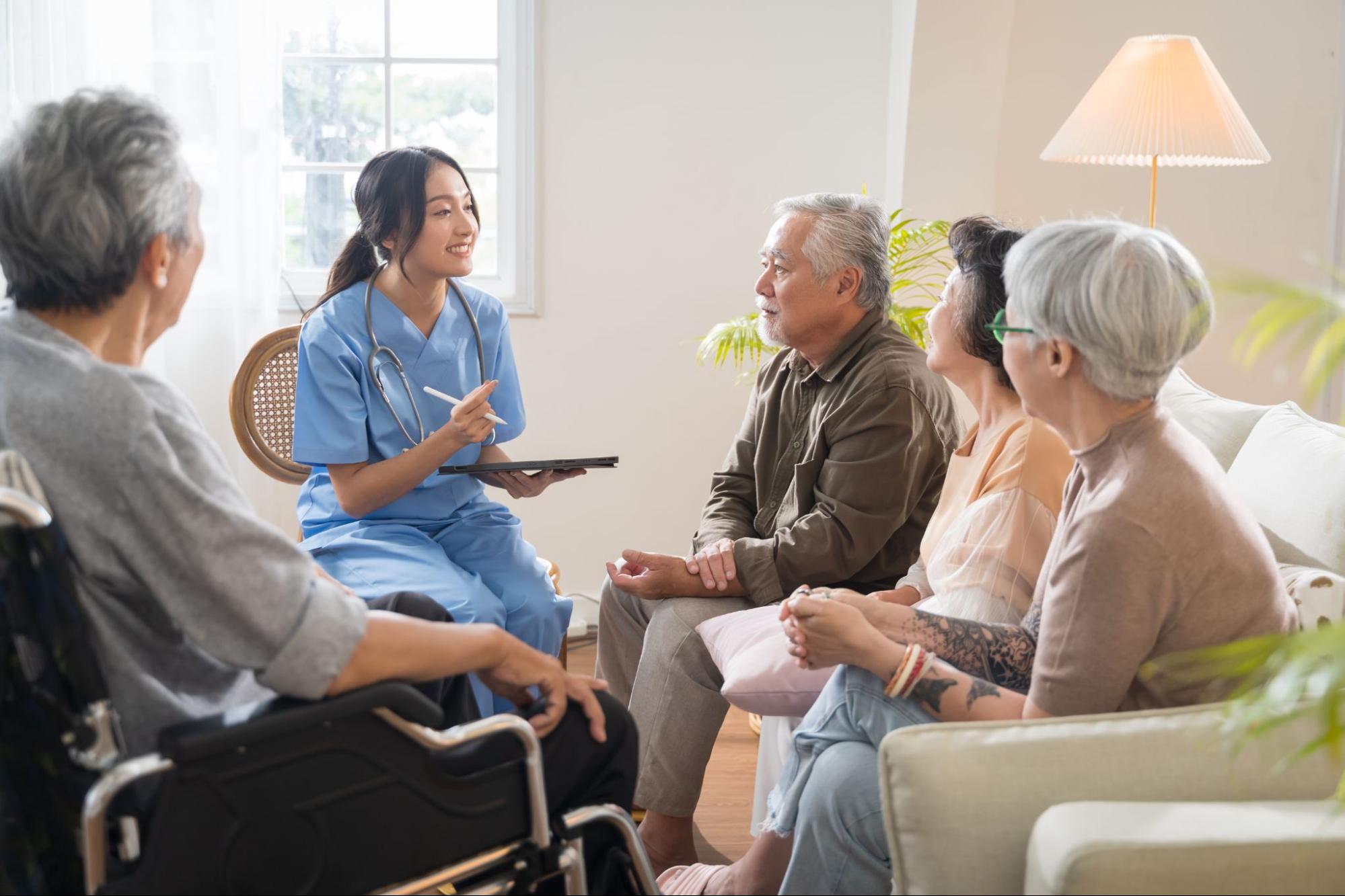 A nurse sitting in a circle with senior citizens.