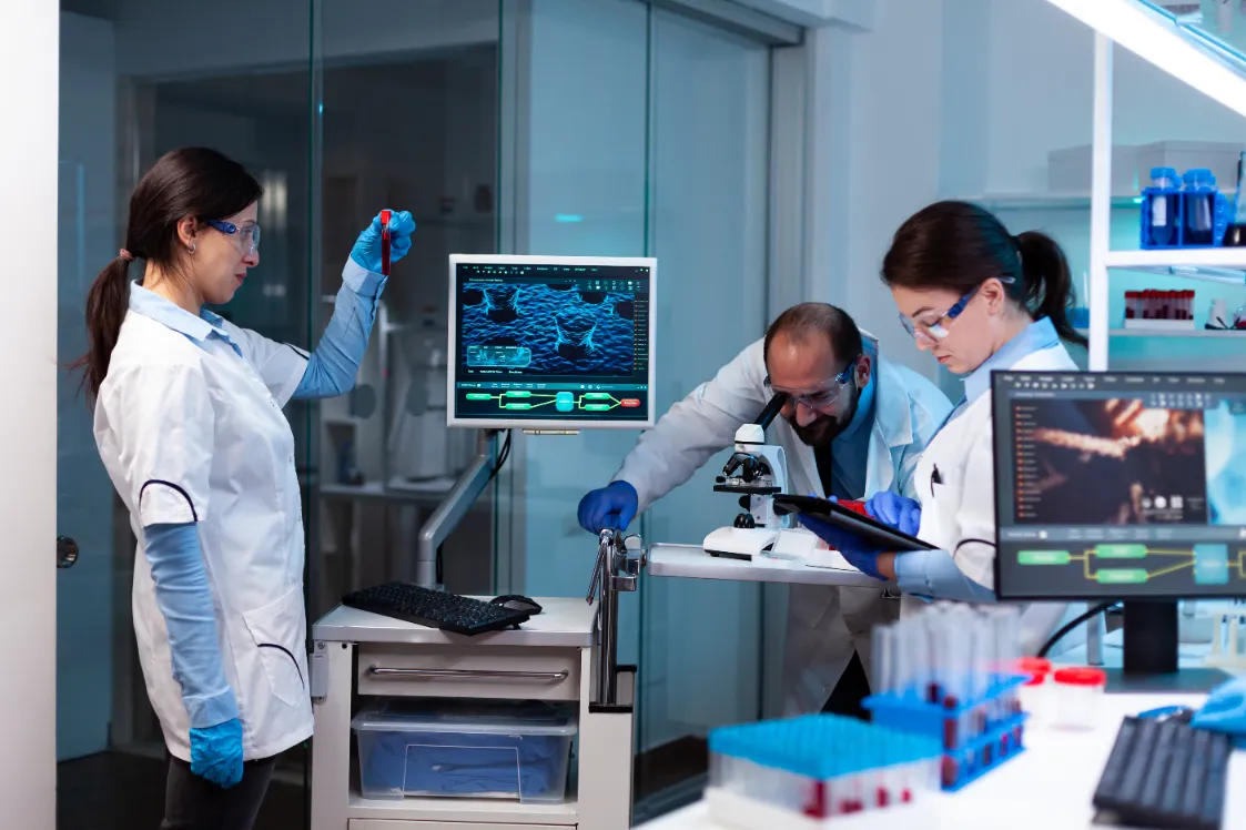 Three researchers examine a blood sample during stem cell research.