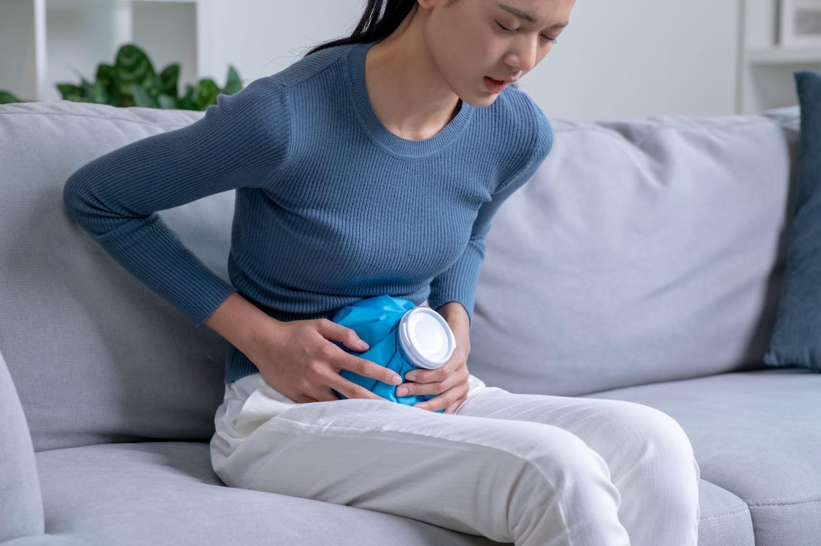 A woman tries holding an ice pack to her stomach to deal with ulcer pain.