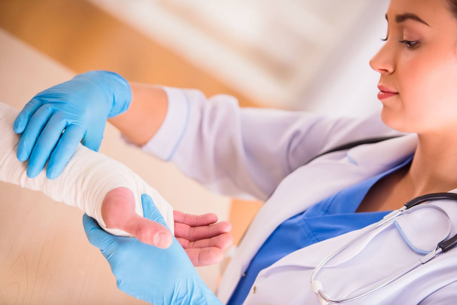 A doctor performs wound care on a patient’s broken wrist.