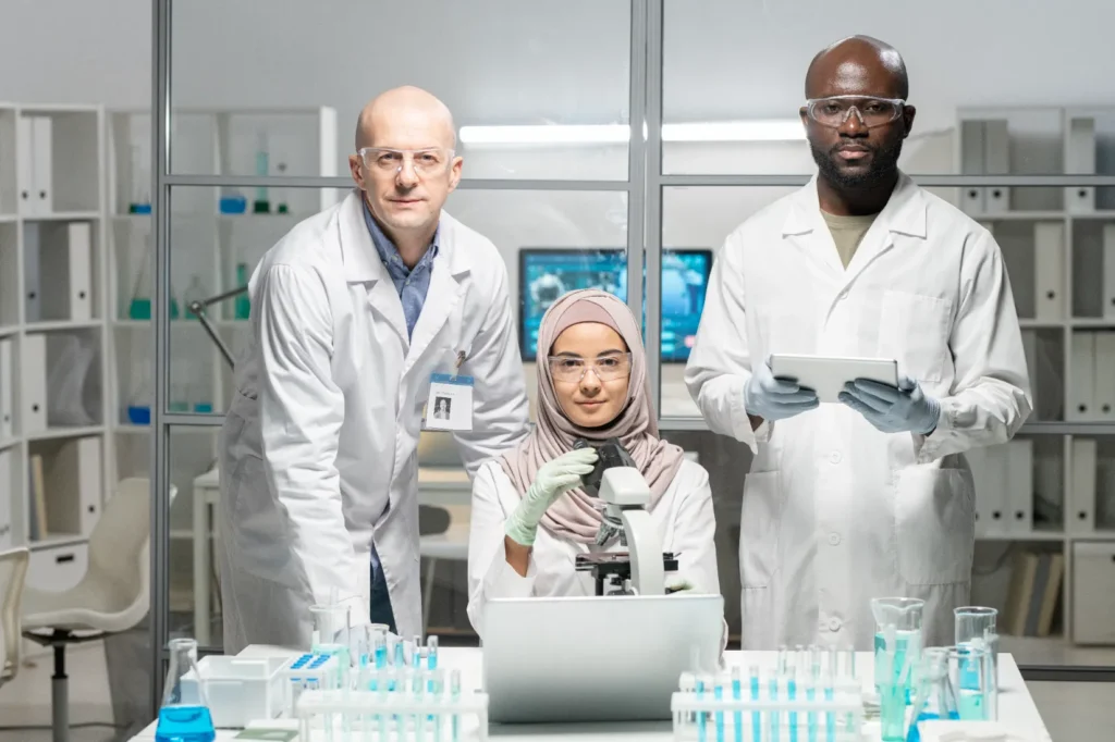 A team of stem cell researchers stand at a desk in lab coats and protective gear.