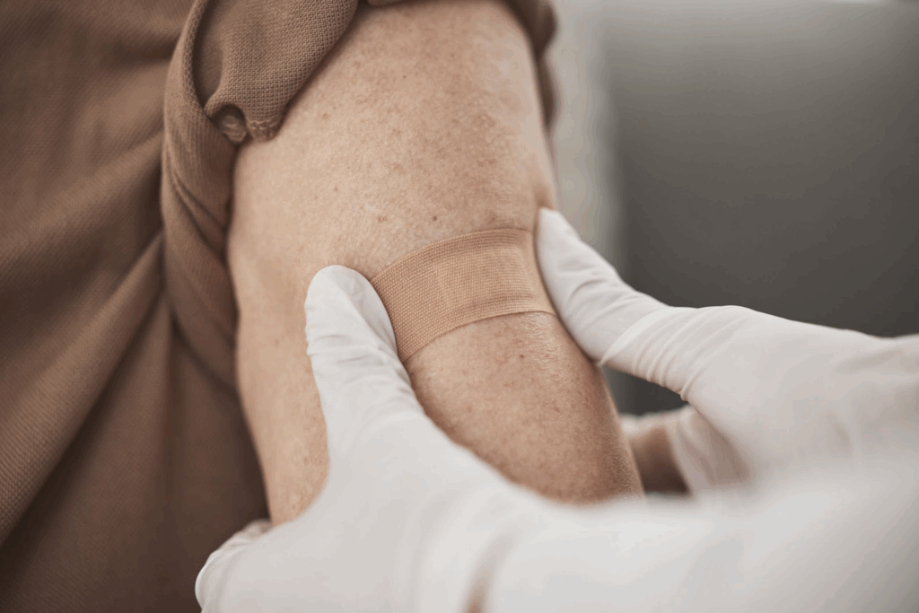 A doctor cares for their patient’s wound by putting a medical strip on their arm.